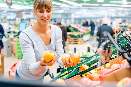 在超市货架上测试新鲜水果的女人