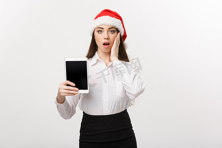 树电子商务摄影照片_企业概念-圣诞节主题的年轻白种人女商人展示数字平板电脑与令人惊讶的面部表情。