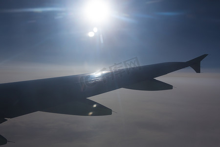 飞机机翼摄影照片_太阳在飞行飞机机翼上方的天空中