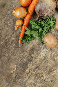 土豆、胡萝卜、洋葱、欧芹、甜菜在质朴的背景上生吃