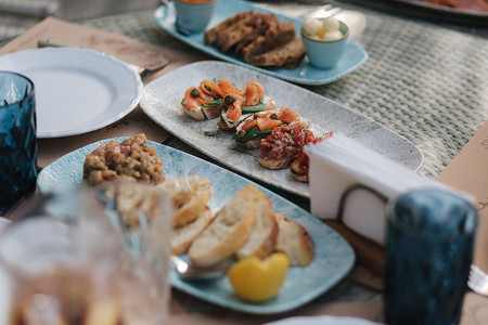 夏季露台餐厅的餐桌上放着美味的意式烤面包，配有红鱼和西红柿。