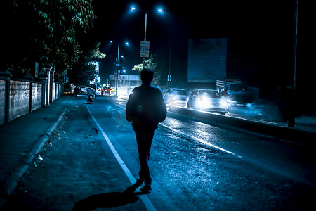 人物剪影摄影照片_夜间交通灯中的人物剪影。