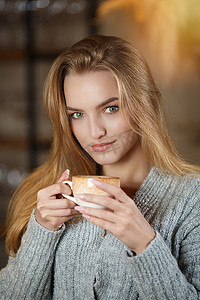 一位年轻美女的画像，她坐在现代咖啡馆酒吧的室内，喝着一杯咖啡