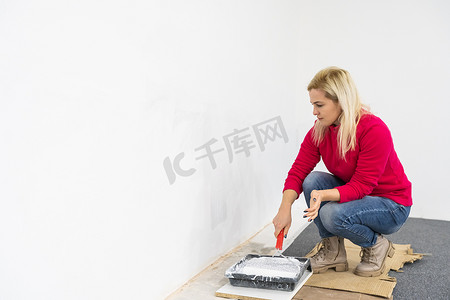 女人在搬进公寓时用滚筒设备粉刷墙壁。