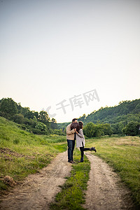 乡村路上的年轻夫妇戴着帽子接吻