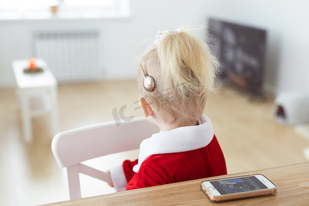 童子童女摄影照片_客厅植入人工耳蜗的聋童女孩-耳聋多样性和创新助听器医疗技术