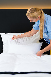 酒店服务，女佣把干净的床单放在床上