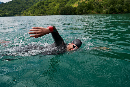铁人三项运动员穿着潜水服在湖中游泳