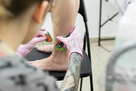 纹身艺术家在一位年轻女子的腿上画了一只瓢虫，这是纹身的过程。