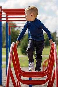 在夏季美好的一天，勇敢的小孩在公共儿童游乐场玩耍和攀登拱形梯子。