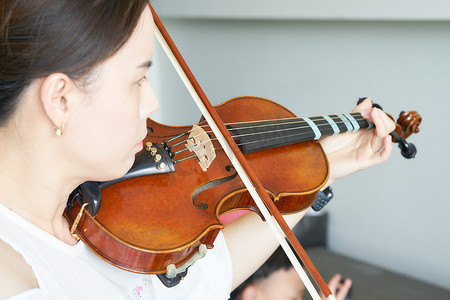 教育x展架易拉宝摄影照片_女人在音乐中拉小提琴，就像音乐家或小提琴家在太阳肖像中表演弦乐
