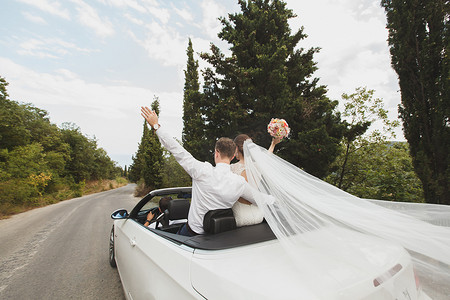 美丽时尚的年轻成功夫妇在热带国家或岛屿的婚礼散步中享受乘坐汽车的乐趣。
