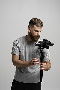 专业留胡子的摄影师电影制片人电影摄影师 dop 拿着设置在 3 轴万向节上的相机。
