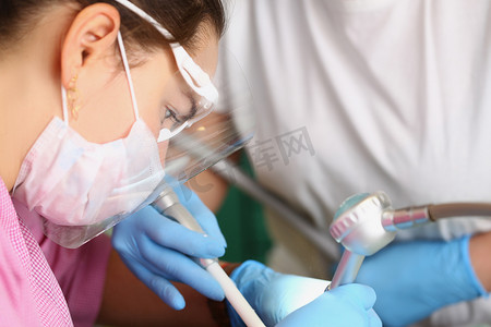 女牙医在预约时治疗患者的牙齿，美白程序