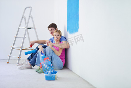 刷蓝色摄影照片_快乐的年轻人在新家刷漆后放松