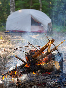 燃烧的篝火，背景是露营帐篷，在森林深处，在日落时分。