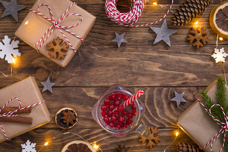 新年圣诞组合物，玻璃杯中配有蔓越莓茶、礼物、木制背景灯