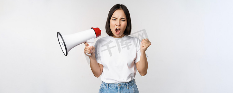看公告的人摄影照片_愤怒的亚洲女孩活动家拿着扩音器，看上去愤怒、抗议，站在白色背景上