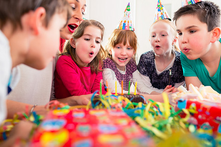 祈福免抠蜡烛摄影照片_生日派对上的孩子在蛋糕上吹蜡烛