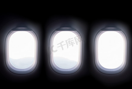 乘飞机旅行摄影照片_乘飞机旅行时，三扇飞机窗户打开白色百叶窗，可以看到山顶