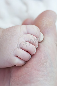 新生儿的脚踩在父亲的脚趾上