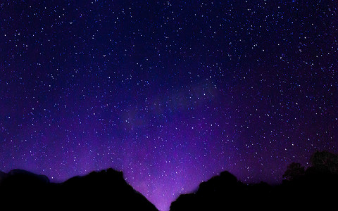 夜空有很多闪亮的星星和模糊的山脉背景。