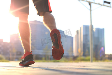 公路奔跑摄影照片_非洲男子在日出或日落时在户外锻炼时双腿奔跑。