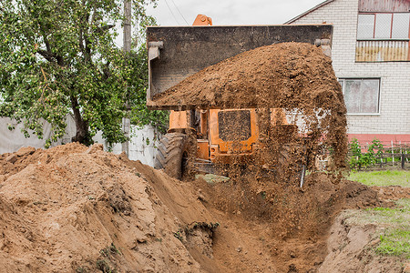 推土机的铲斗在工业区用泥土填满沟渠。