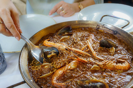 海鲜肉类摄影照片_西班牙海鲜饭，指制作食谱的容器，并以此命名，是一种以米饭、海鲜或肉类为基础的烹饪食谱，起源于当前的西班牙瓦伦西亚社区。