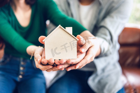 情侣手握未来房地产储蓄的住房模型，人们携手保护家庭财产团结。