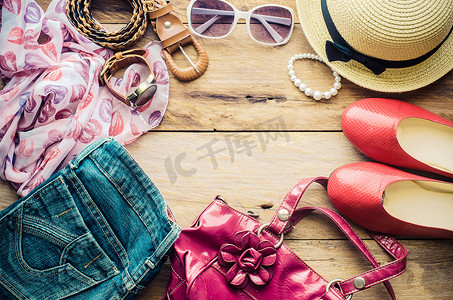 鞋子配饰摄影照片_少女度假时的配饰、帽子、时尚的夏季太阳镜、皮包、鞋子和木地板上的服装。