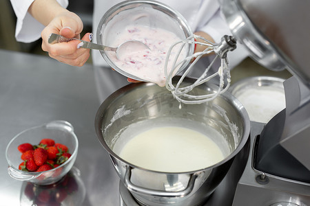 糕点师将奶油和草莓加入搅拌机的碗中并揉成面团