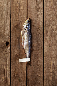 粗糙木质背景尾部带标签的盐渍风干波罗的海鲱鱼