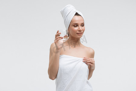 自信放松的女人，头上戴着白毛巾，喝着纯净水，看着别处