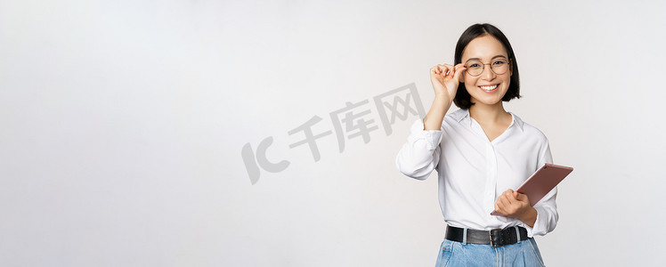 年轻的亚洲女商人、戴眼镜的女企业家、手持平板电脑、戴着眼镜、白色背景的专业形象