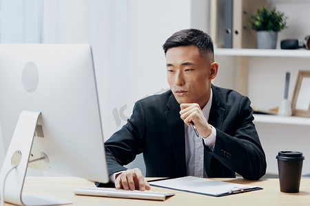 坐在电脑前的办公桌前的亚洲男人
