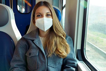 2ba摄影照片_戴着防护面罩的年轻女性在火车上看着相机旅行