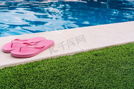粉红色的拖鞋，适合游泳池或海滩的草地，有游泳池底部。