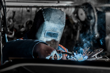 防护罩中的焊工工业工人在工厂从事焊接和金属加工
