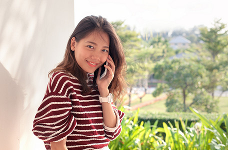 年轻的亚洲女性带着幸福的心情用智能手机交谈