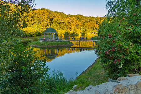 休闲凉亭位于湖中央的一个绿色岛屿上，有一座桥通向它。