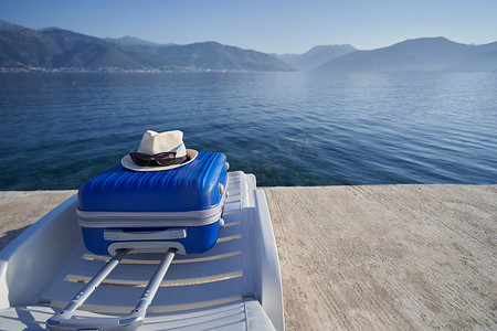 黑山亚得里亚海沿岸日光躺椅上的蓝色手提箱，旅游概念