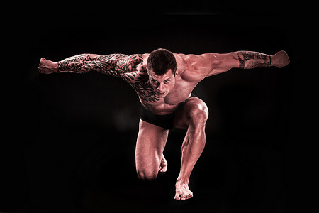 健美运动员摄影照片_肌肉男健美运动员站在膝盖上时展示了他的肌肉。