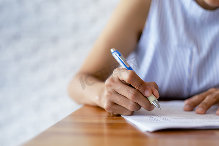 商业女性的特写手使用笔书写文档纸。