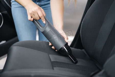女性在她的车里使用便携式真空吸尘器的特写。