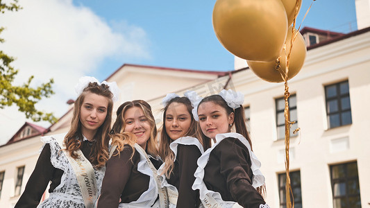 在上学的最后一天，欢快的俄罗斯女孩带着橙色气球毕业。