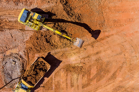 装入摄影照片_挖掘机将土装入自卸卡车的空中俯视图