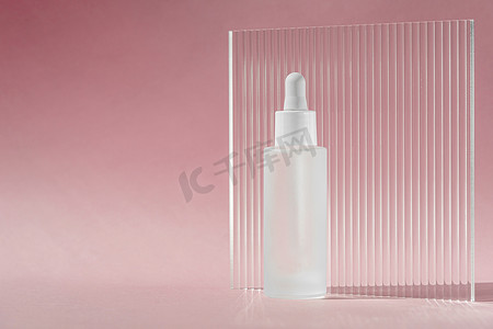 白色透明瓶中含有胶原蛋白和肽的血清油，粉红色背景上带有滴管，带有丙烯酸肋板。