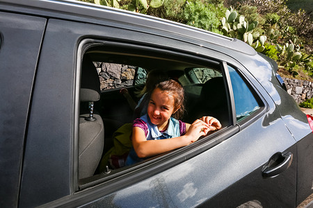 小有趣的女孩在开着的窗户附近的车里加速