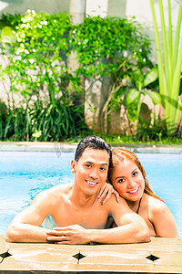 亚洲夫妇在度假村游泳池游泳